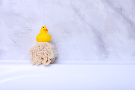 Children's hygiene products concept. Yellow duckling in the bathroom on a background of gray tiles. Copy spaceの写真素材