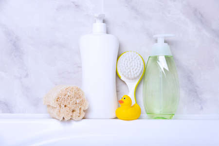 Children's hygiene products concept. Yellow duckling in the bathroom on a background of gray tiles. Copy spaceの写真素材