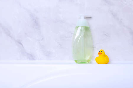 Children's hygiene products concept. Yellow duckling in the bathroom on a background of gray tiles. Copy spaceの写真素材