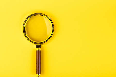 Magnifying glass in a gold frame on a yellow background. Copy space.の写真素材