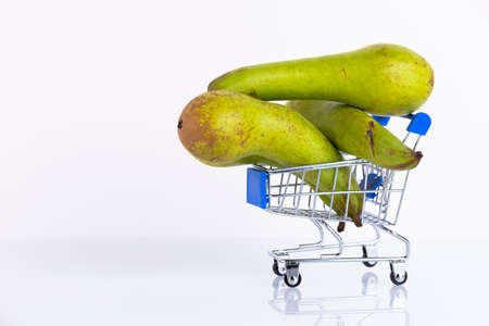 Green conference pears in a shopping cart, on a white background. Copy space.の写真素材