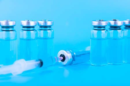 Medical ampoules and syringe on a blue background. Copy space. Selective focus