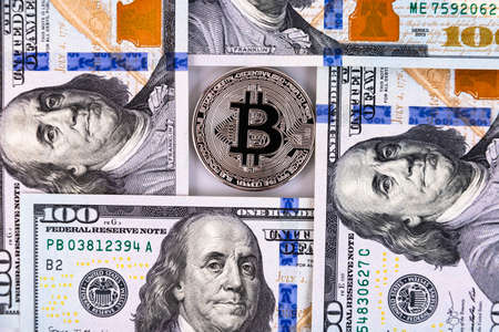 Platinum bitcoin on the background of one hundred dollar bills