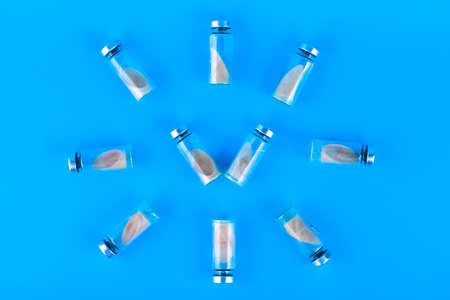 Vials, ampoules with a dry probiotic, bifidobacteria inside on a blue background are laid out in the...