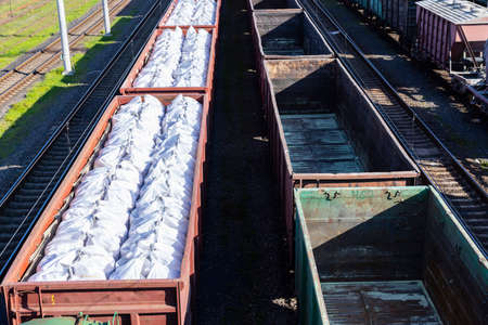 Coal wagons and mineral fertilizers in large packages as part of a train.