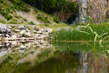 View of the coastline of a mountain lake in the foreground with large stones and reflection in the water. Scenery.の写真素材