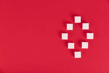 White sugar cubes on a red background in the form of the number zero.Copy space.の写真素材
