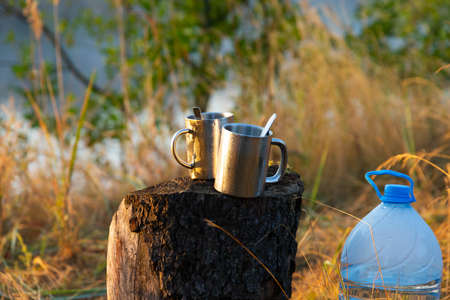 Picnic in nature. Two metal thermal cups with spoons stand on a tree stump.の写真素材