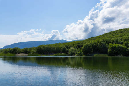 Mountains surround the mountain lake. The surface of the lake reflects sunlight. Landscapeの写真素材