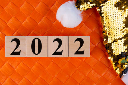 New year numbers 2022, golden santa claus hat and beard on orange background, creative minimal christmas conceptの写真素材