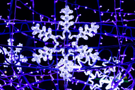 Beautiful christmas decoration on the streets of Europe, bright glowing neon snowflake