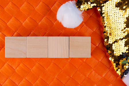 Concept for writing text from four letters or numbers on wooden cubes lying on an orange surface and with a Santa Claus hat. Copy space.の写真素材