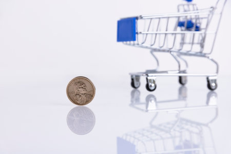 Coin one American dollar on the background of a supermarket trolley on a white background. Copy space. Selective focusの写真素材