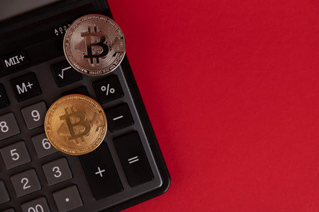 Calculator, Bitcoin coins on a red background. Copy space.の写真素材