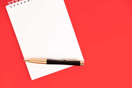 White notepad with a stylish pen on a red background. Copy space.の写真素材