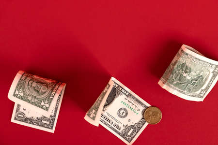 American banknotes and coins are scattered over a red background. Copy space.の写真素材