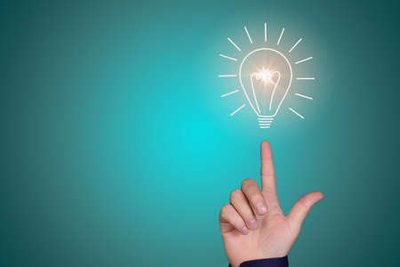 Light bulb on the fingertip of a man's hand on a blue-green background