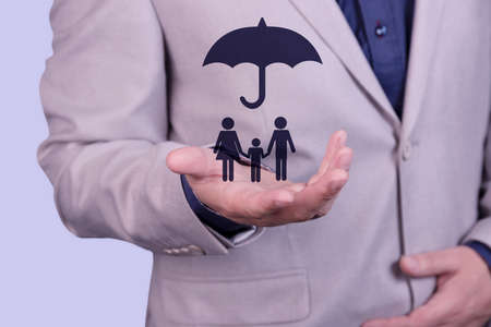 A businessman holds an umbrella on his hand, over a family concept, for protection, safety, finance and insurance. High quality photoの写真素材