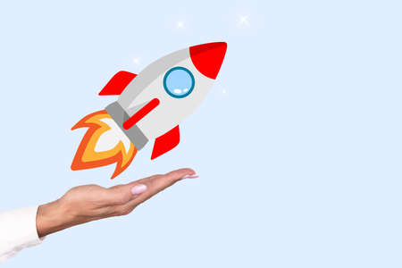 Startup concept. Business woman's hand launches a rocket on a blue background. Copy space. High quality photoの写真素材