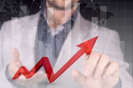 Stock market growth graph, manipulations with forex, the hand of a businessman indicates a red graph of growth and profit, a red danger zone against the background of the world map. Double exposure. High quality photoの写真素材
