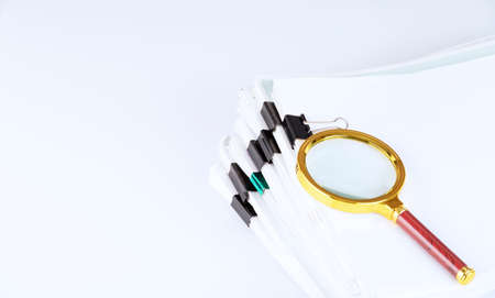 stack of paper documents with a magnifying glass on the office table. business and search concept....