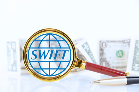 SWIFT. Magnifying glass on the background of American banknotes. The concept of financial regulation sanctions.の写真素材