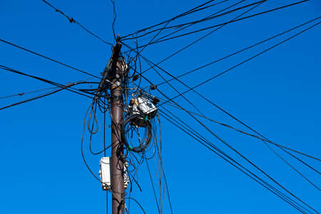Internet, wires and cable on a distribution pole on the street against the blue sky.の写真素材