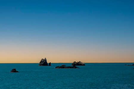 Seascape with lonely wild rocks in the water at dawn.