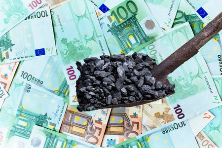 Black coal on a shovel against the background of Euro paper banknotes. Energy crisis in Europe.