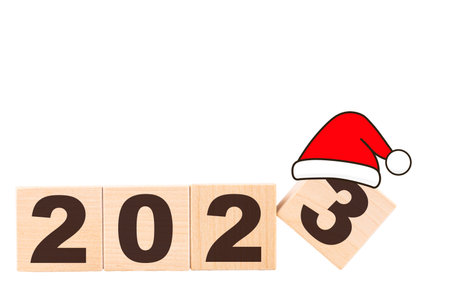 2023, New Year's numbers made up of wooden cubes and Santa Claus hat. White isolated background....