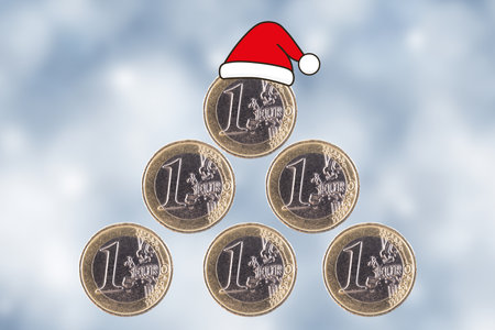 christmas tree. One Euro coins are stacked in the form of a pyramid and a Santa Claus hat on a blurred New Year's background.の写真素材