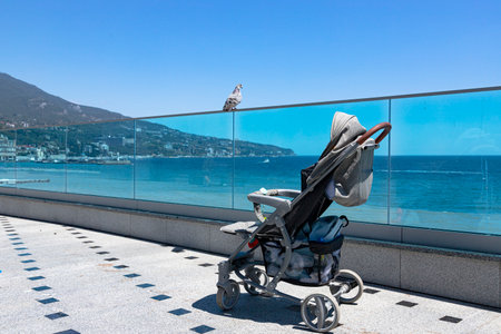 An empty baby stroller stands on the promenade by the sea.の写真素材