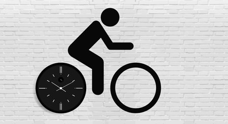 Cyclist on a bicycle with a clock and a dial in the form of bicycle wheels against a gray brick wall. Copy space.の写真素材