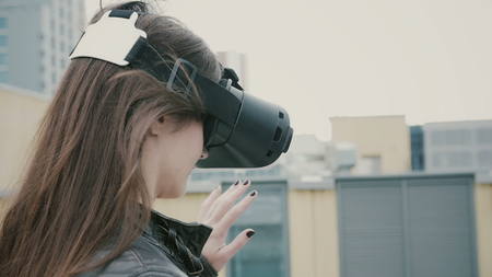 Brunette woman uses a virtual reality glasses on the roof. 4k