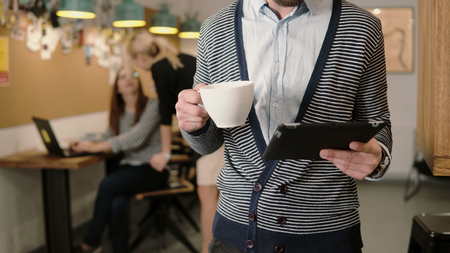 close-up of hands young man uses touchscreen tablet and drinking coffee in the modern startup office team in the workplaceの写真素材