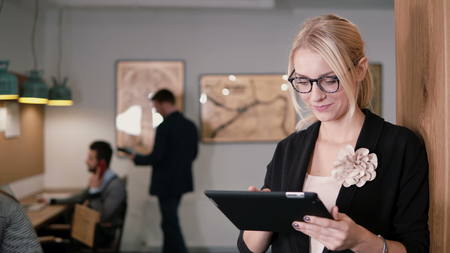 4k. beautiful blonde businesswoman uses a touchscreen tablet in the modern startup office.の写真素材