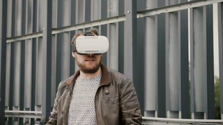 bearded man uses virtual reality glasses in the urban space. 4k