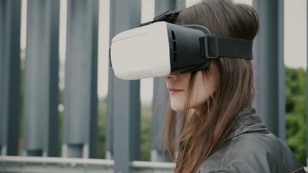 Brunette woman uses virtual reality glasses in the urban space. 4k
