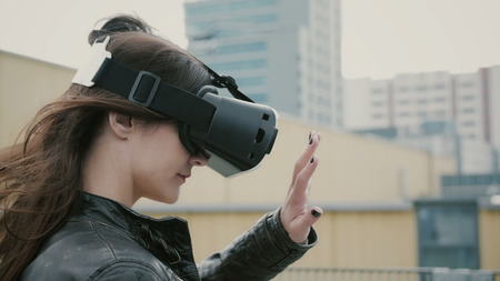 Brunette woman uses 3D Virtual Reality headset on the roof. 4kの写真素材
