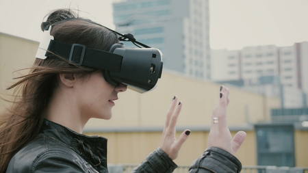 Brunette woman uses 3D Virtual Reality headset on the roof. 4kの写真素材