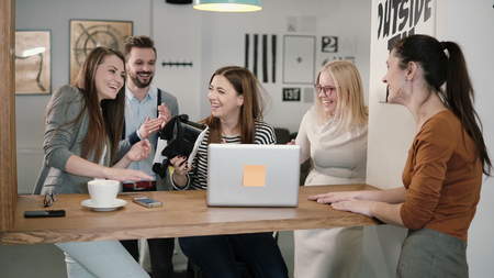 young brunette girl takes off her virtual reality glasses after using the new application. Woman emotionally share experiences with a team of friends in the modern startup office.の写真素材