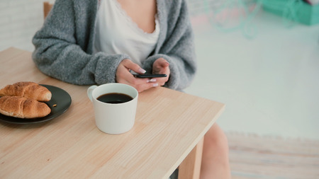 Close-up view of woman having breakfast and browsing Internet, using touchscreen. Girl reads new on...