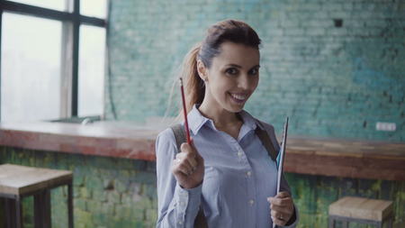 Young caucasian woman in modern coworking space. Portrait of beautiful female holds the documents,...