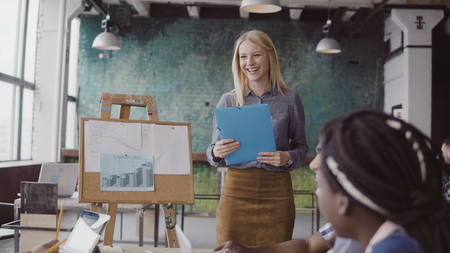 Meeting of multiethnic young business team. Beautiful woman manager presenting financial data to group of people.の写真素材