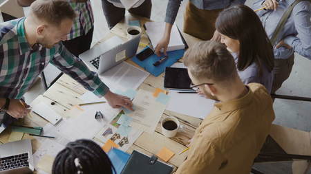 Top view of mixed race group of people standing near the table. Young business team working on start-up project togetherの写真素材