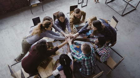 Top view of business team working at trendy loft office. Young mixed race group of people puts palm together on centre.の写真素材