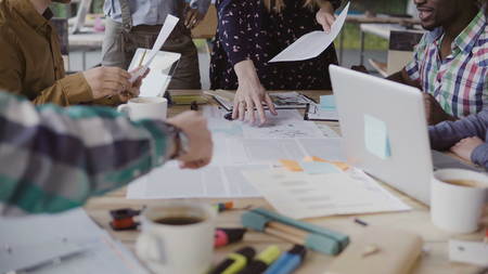 Female manager presenting the project, handing out the paper document. Business meeting of young mixed race team.の写真素材