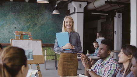 Close-up view of female manager walking through the office with documents. Multiracial team clap to businesswoman.の写真素材