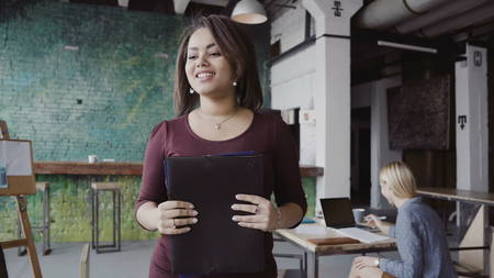 Young african team leader walking through modern office and controls work of employee. Female looks the fabric examples.の写真素材
