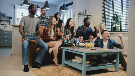 Multi-ethnic fans celebrate success. Wide shot. Crazy football sports supporters shout in euphoria. 4K slow motion.の写真素材